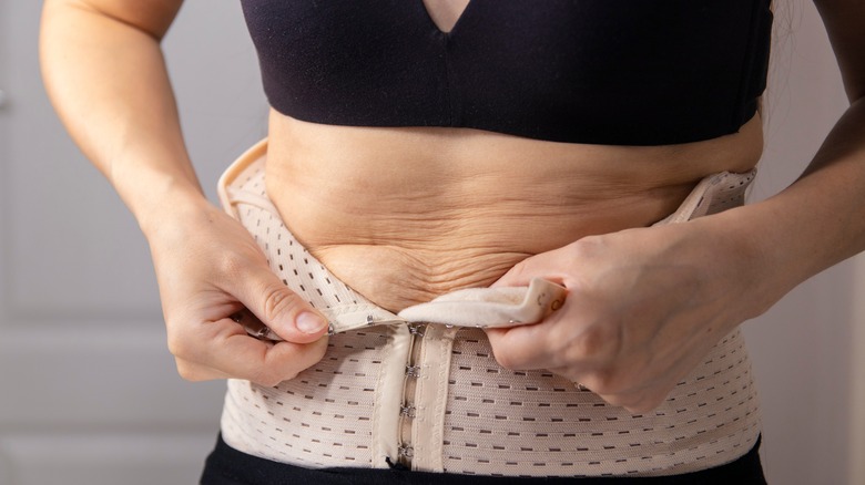 woman putting on corset shapewear