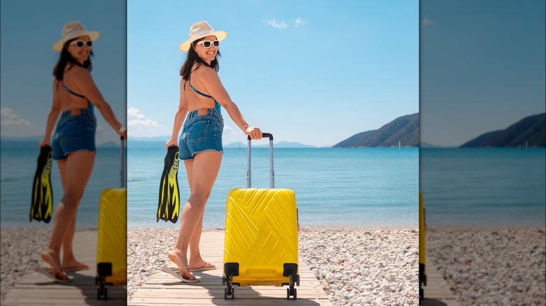 Woman wearing swimsuit carrying suitcase