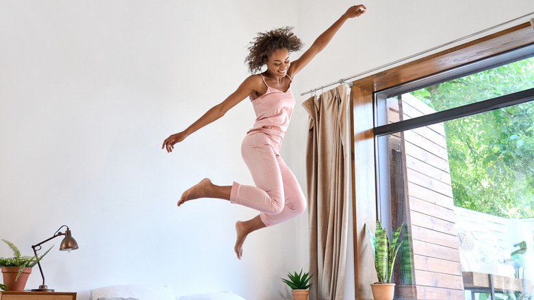 happy woman jumping on bed