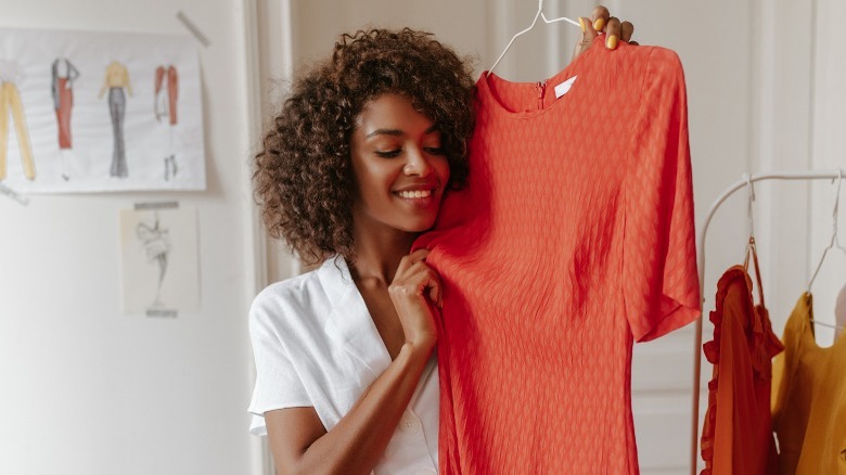 Woman holding up dress on hanger