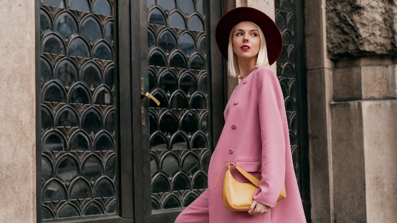 Woman with pink coat, red hat, and yellow purse