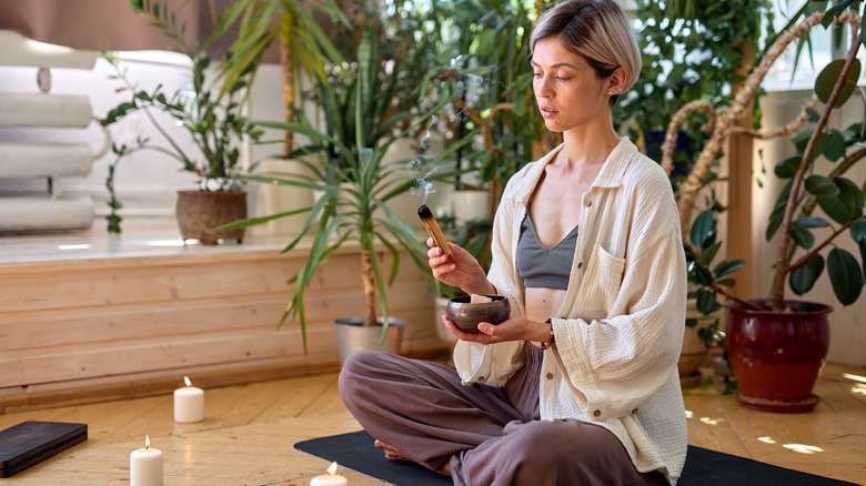 Woman meditates on wood floor wearing brown