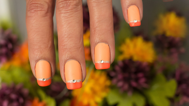 Orange polish manicure on fingers