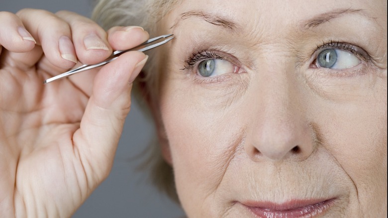 Woman tweezing eyebrows