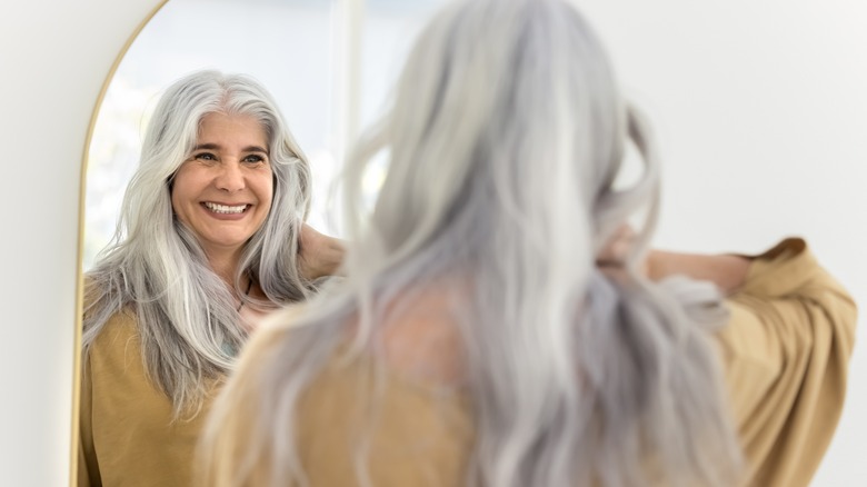 White-haired woman looking in mirror