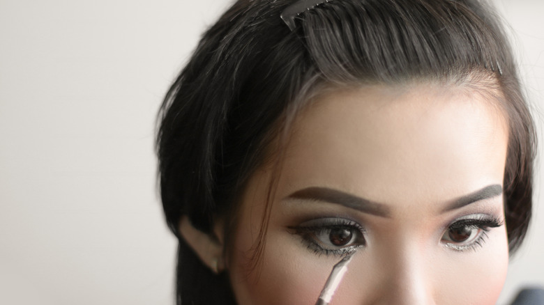 A woman doing her eye makeup