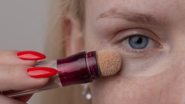 A woman applying concealer