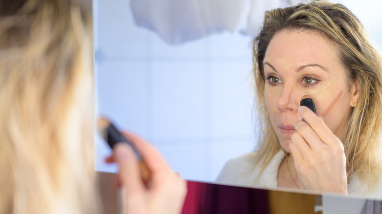 A woman applying concealer