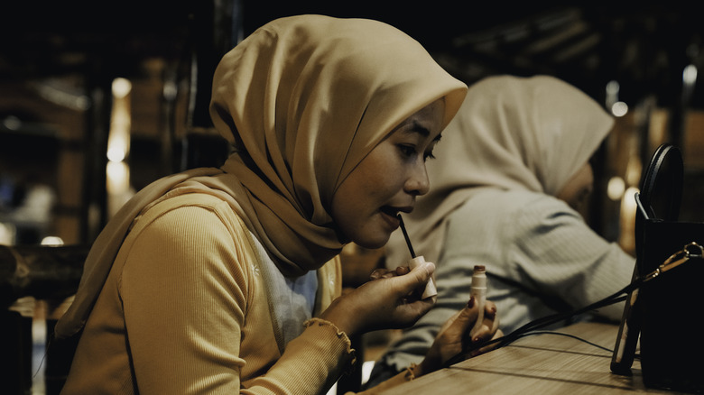 A woman applying lipgloss