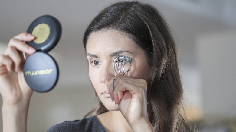 A woman curling her eyelashes