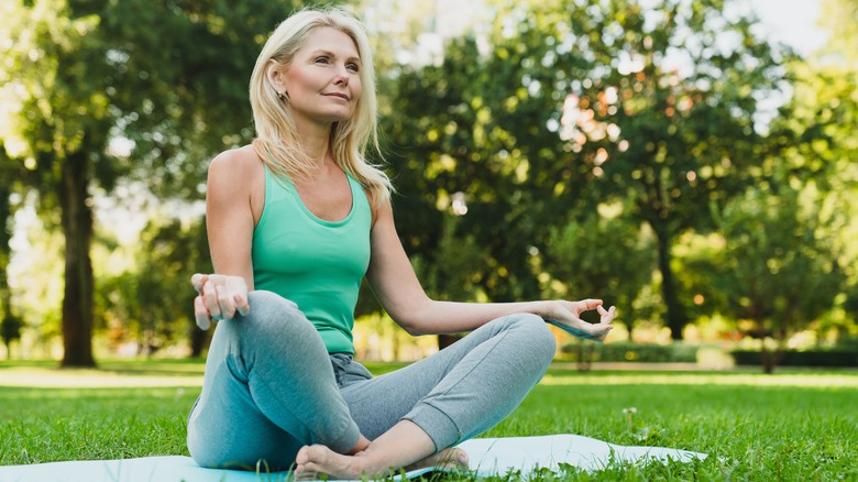 Older woman on lawn in peaceful yoga pose