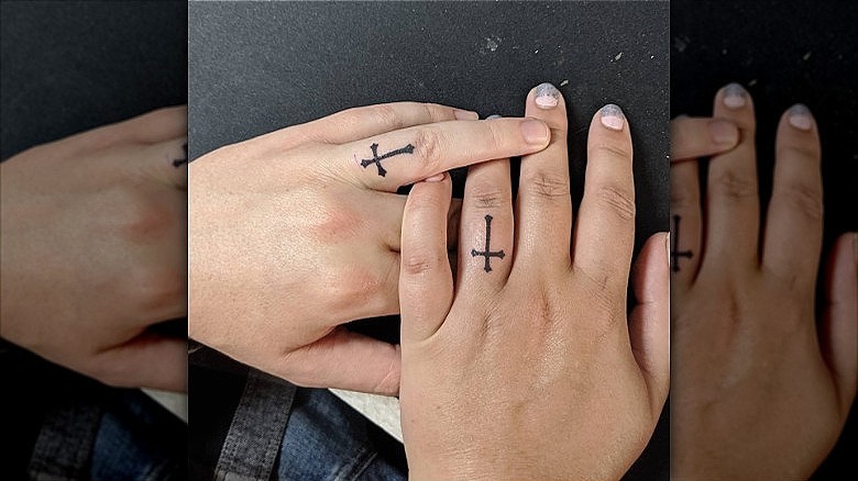 couple wearing cross ring finger tattoos