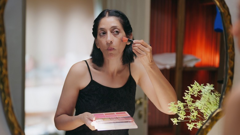 Woman applying makeup to her cheeks