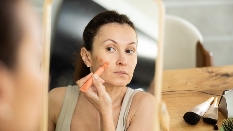 Woman applying orange contour to her face