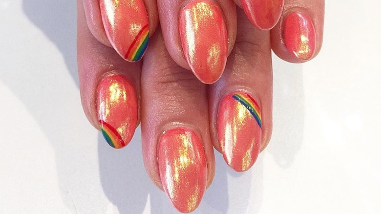 Woman wearing coral glazed nails with a rainbow design