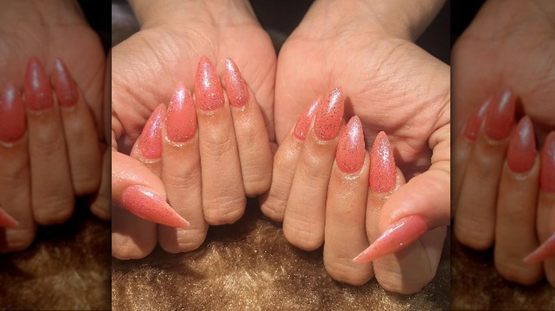 Woman wearing coral glazed nails with silver glitter