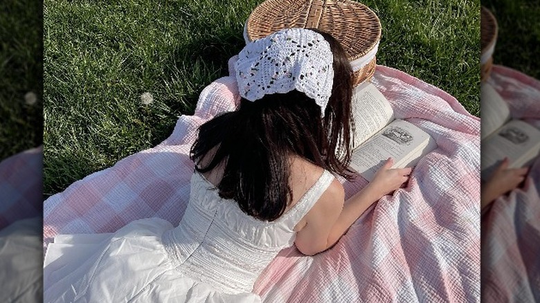 woman reading book on picnic blanket