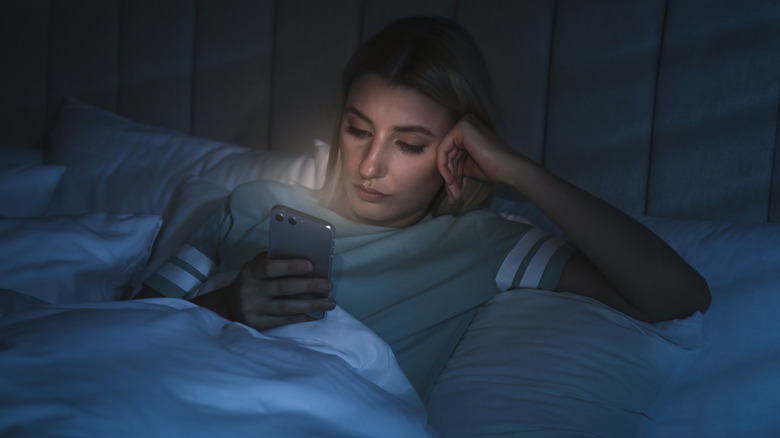 Woman using phone in bed