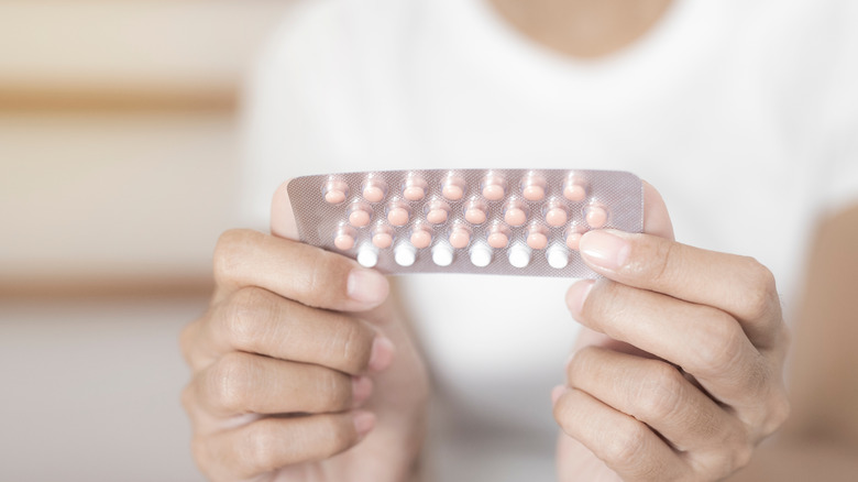 Close up of hands holding oral contraceptives