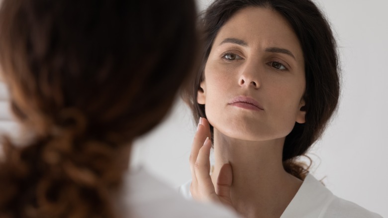 Concerned woman checking her face in mirror