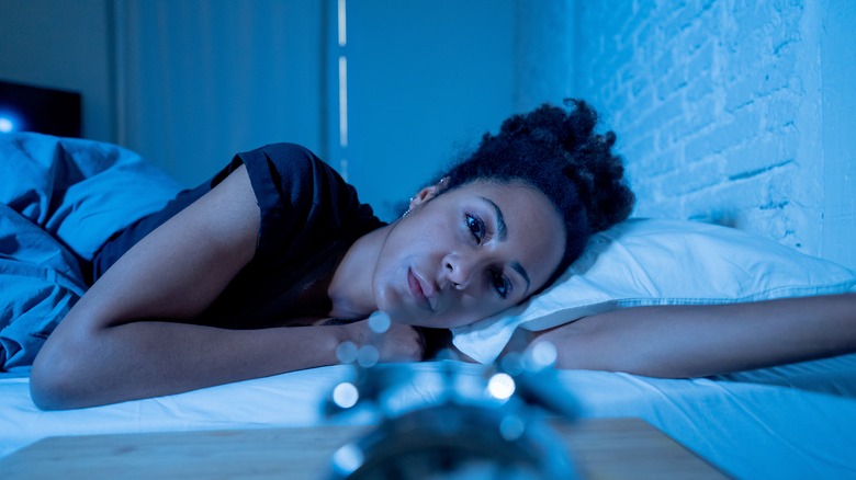 Woman wearing flannel pajamas, awake in bed