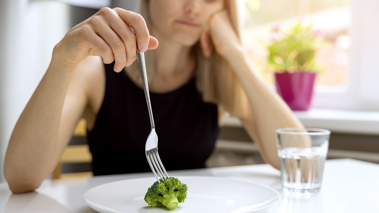 Woman with a piece of broccoli on her plate