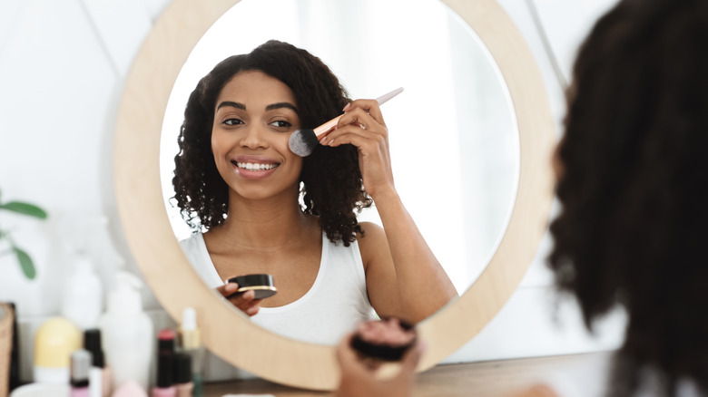  woman applying blush in mirror