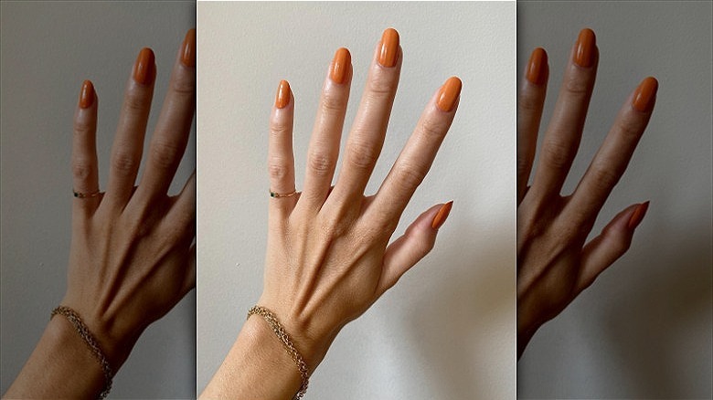 woman with muted orange creamsicle nails