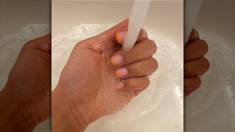 woman with thin creamsicle french tip nails