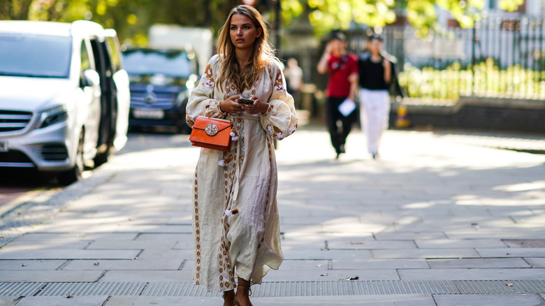 Woman in boho dress holds mini satchel bag