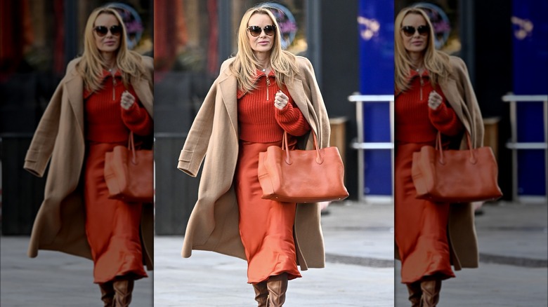 Woman holding oversized orange handbag