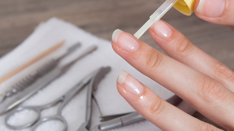 Woman applying oil on her cuticles 