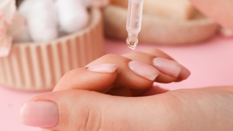 Woman putting oil cuticle on nails