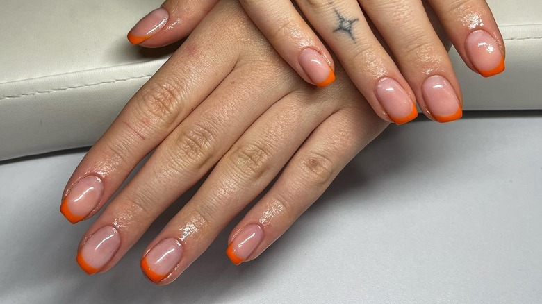 Hands with orange French manicure