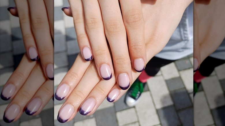 Hands displaying plum French manicure