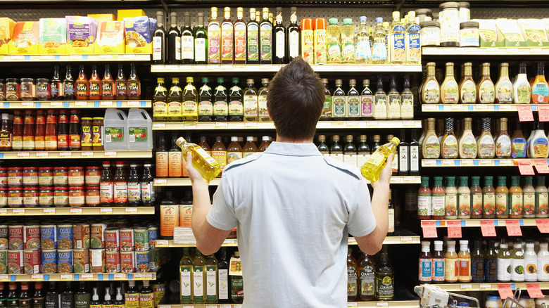 Customer debating olive oils in supermarket