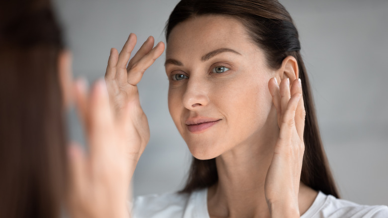 woman looking in mirror and touching face