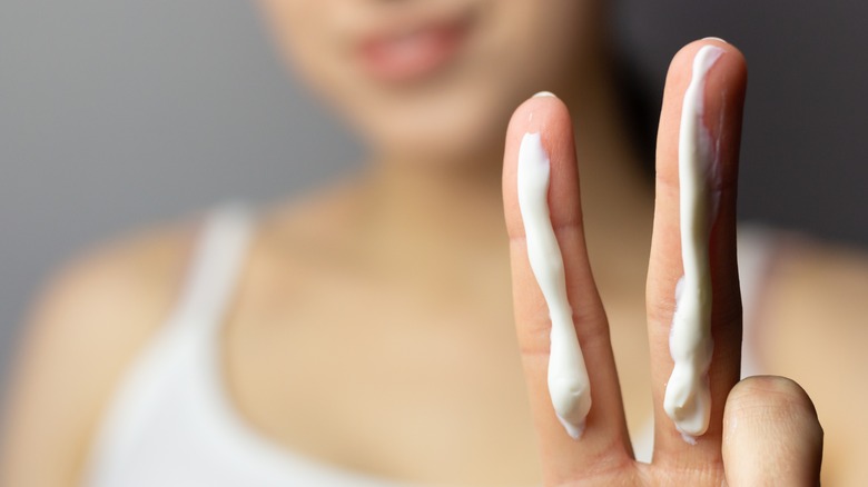 Woman holding up two fingers with sunscreen