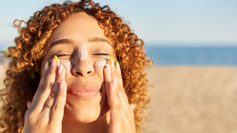 Smiling woman applying sunscreen to face