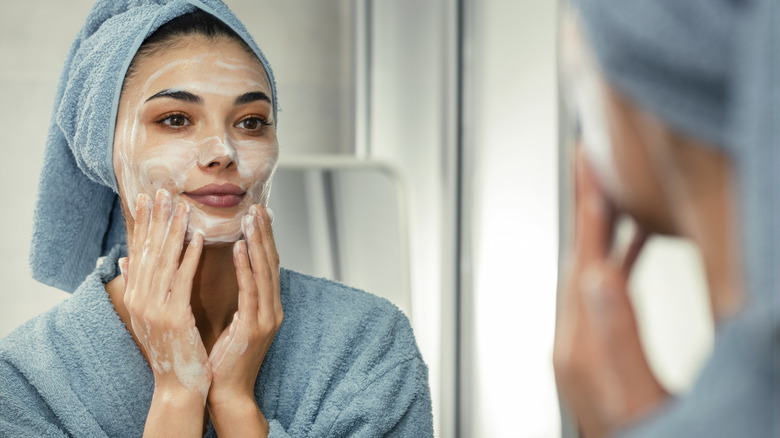 Woman in blue towel with suds on her face