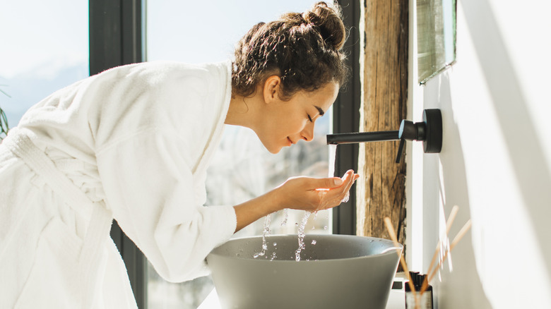 Woman washing her face over a sink