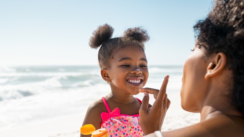 Woman putting sunscreen on daughter