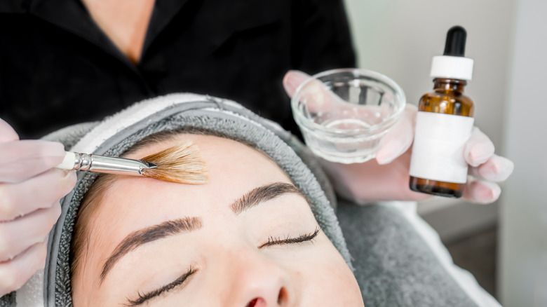 Beautician applies serum to client