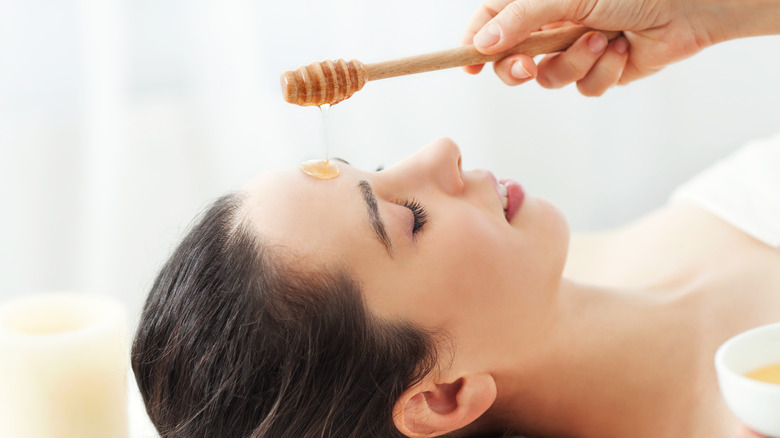 Honey being applied to a woman's face