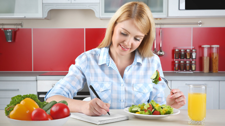 woman logging food in notebook