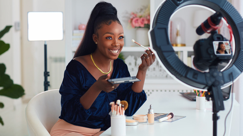 Woman applying makeup with camera and ring light