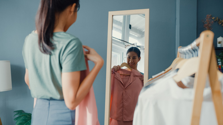 woman looking in the mirror with clothing in hand