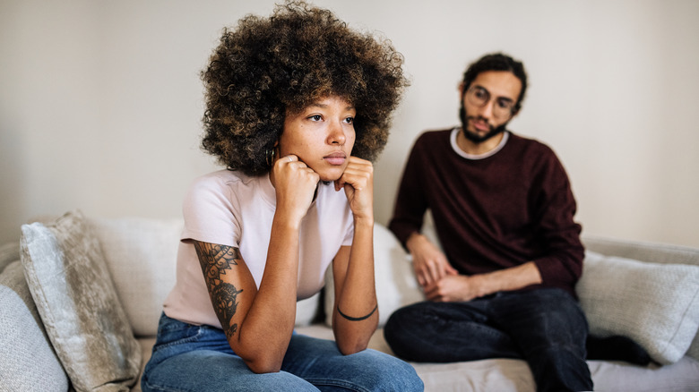 Couple on sofa looking unhappy