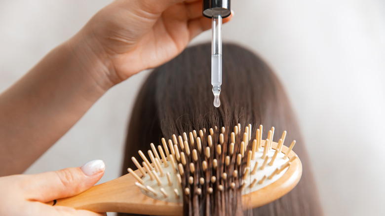 applying oil while brushing hair