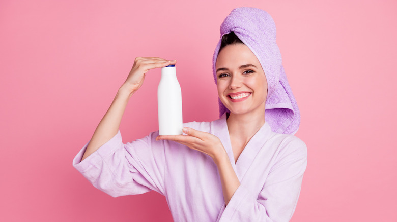 woman holding up shampoo bottle